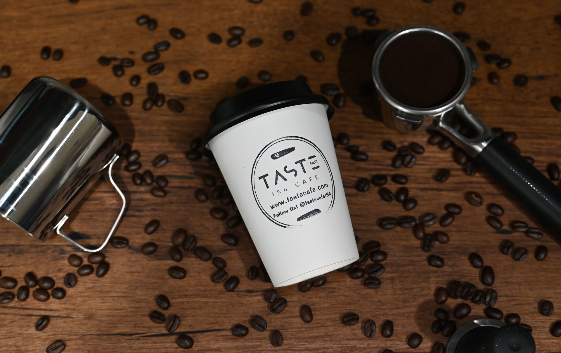 A Taste 154 cup beside an espresso portafilter and scattered coffee beans