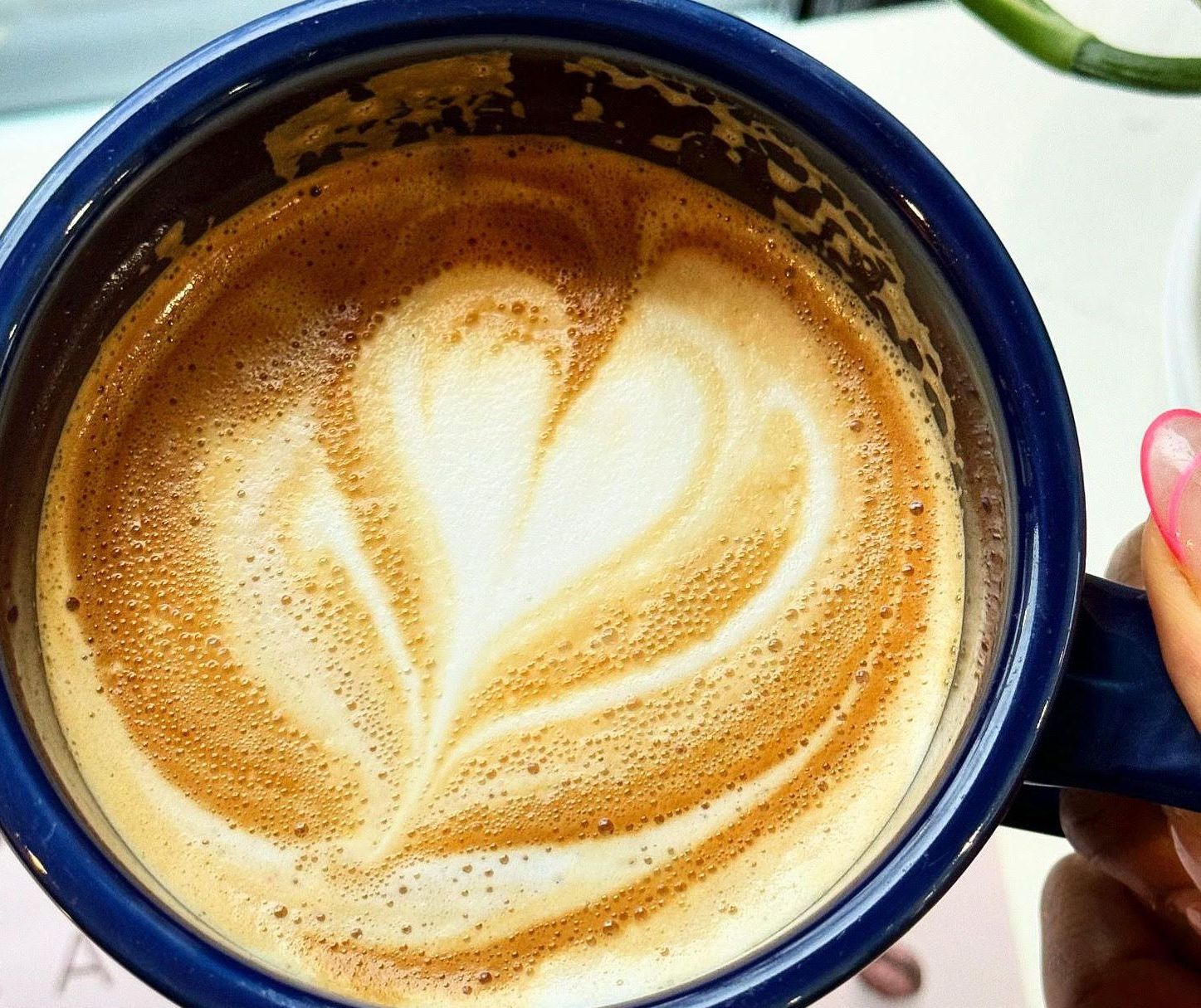 A cappuccino with rosetta latte art in a deep blue cup at Taste 154